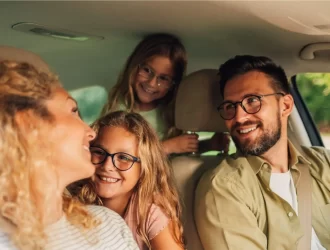 família de 4 pessoas dentro de um carro, homem, mulher e duas crianças