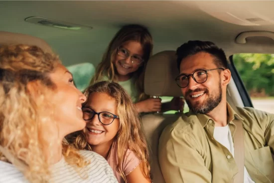 família de 4 pessoas dentro de um carro, homem, mulher e duas crianças