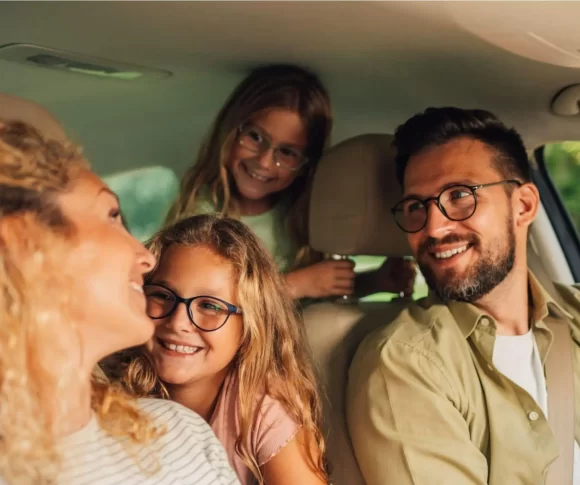 família de 4 pessoas dentro de um carro, homem, mulher e duas crianças