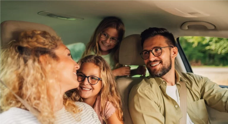 família de 4 pessoas dentro de um carro, homem, mulher e duas crianças