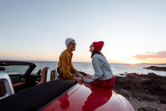casal em um pôr do sol na praia sentado em um carro