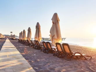 céu azul e sol em uma praia na Europa, areia e várias cadeiras com guarda-sol