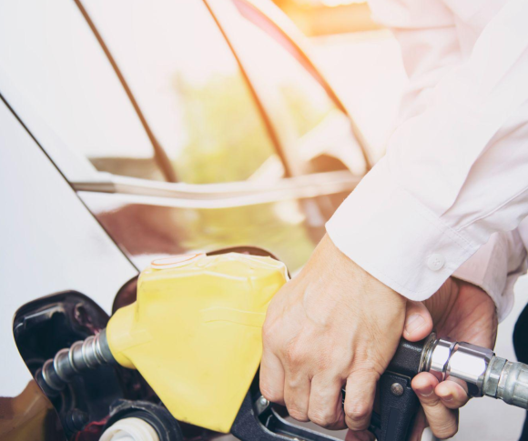 Homem colocando gasolina em seu carro em um posto de gasolina