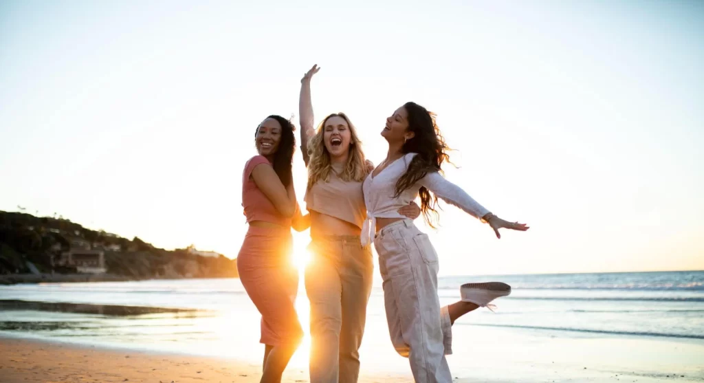 três mulheres se abraçando na praia