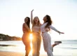 três mulheres se abraçando na praia