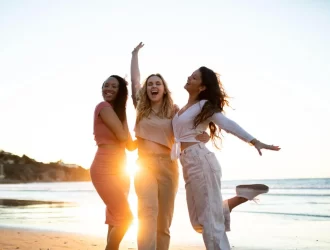 três mulheres se abraçando na praia