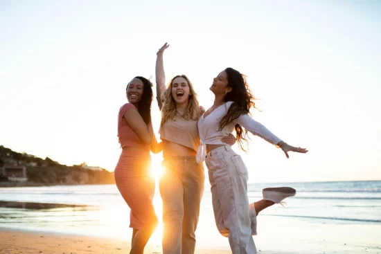 três mulheres se abraçando na praia