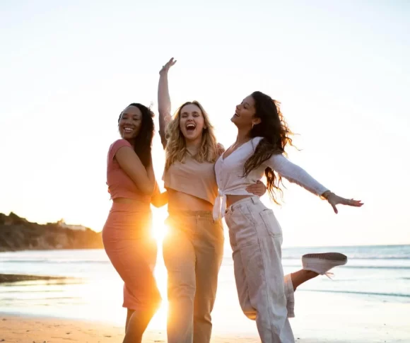 três mulheres se abraçando na praia