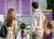 Familia esperando en el aeropuerto frente a la pantalla de salidas y llegadas tras un retraso de vuelo