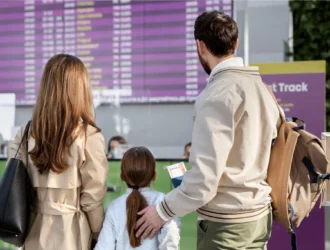 Familia esperando en el aeropuerto frente a la pantalla de salidas y llegadas tras un retraso de vuelo