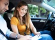 Aquí tienes la traducción directa de la frase aplicando la conjugación de tú (asumiendo el papel protagónico en la acción): "Una pareja en el interior de un carro en movimiento, contigo sonriendo mientras ajustas o sujetas el tablero, y el hombre a tu lado, ambos usando cinturones de seguridad y manejando con atención al tránsito