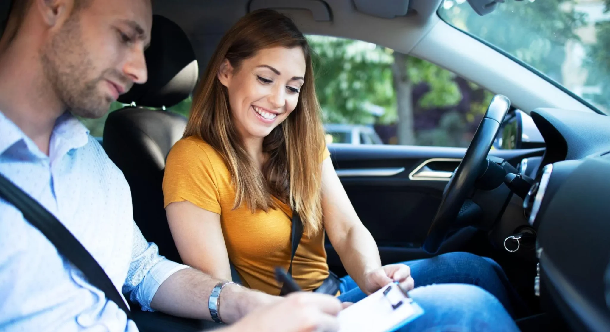 Aquí tienes la traducción directa de la frase aplicando la conjugación de tú (asumiendo el papel protagónico en la acción): "Una pareja en el interior de un carro en movimiento, contigo sonriendo mientras ajustas o sujetas el tablero, y el hombre a tu lado, ambos usando cinturones de seguridad y manejando con atención al tránsito