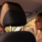 Casal dentro do carro durante um passeio, com o motorista ao volante e a passageira sorrindo ao lado pela janela, em clima de conversa e tranquilidade.