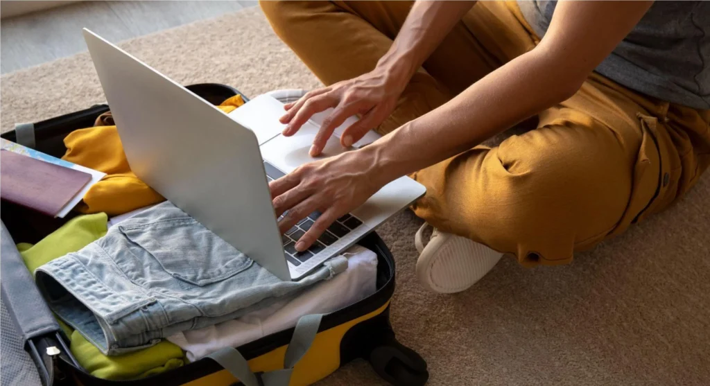 Pessoas trabalhando em equipe com um notebook aberto no chão, com roupas dobradas ao lado, ambiente doméstico e colaboração para organizar ou planejar tarefas