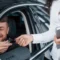 Atendimento em carro: motorista sorridente recebe as mãos de um consultor que entrega a chave do carro, sugerindo suporte ou verificação de informações durante a entrega.